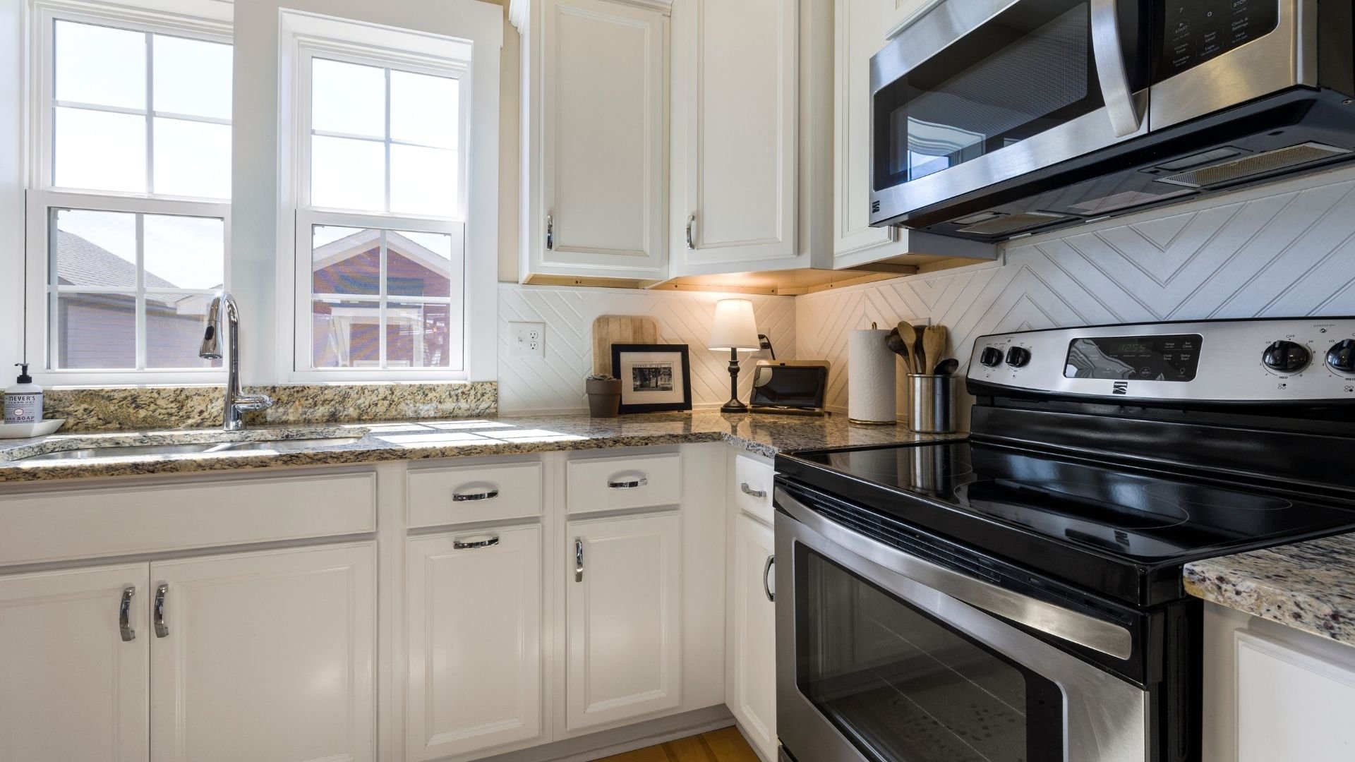 Modern kitchen with cream cabinets, granite countertop, stainless steel appliances, and natural light.